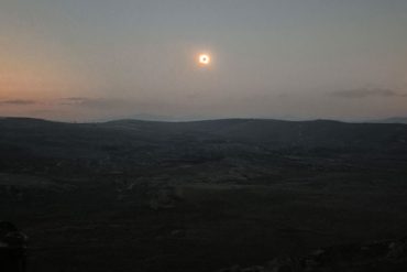 Die ringförmige Sonnenfinsternis leuchtet als schmaler heller Ring am Abendhimmel über einer dunklen Berglandschaft in Nordspanien.